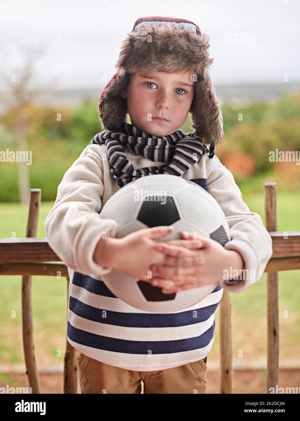 Nothing will keep me from playing. Shot of a little boy standing outside with his soccer ball. Stock Photo