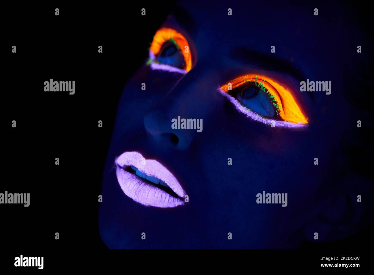 Bright eyes. A young woman with with neon paint on her face posing