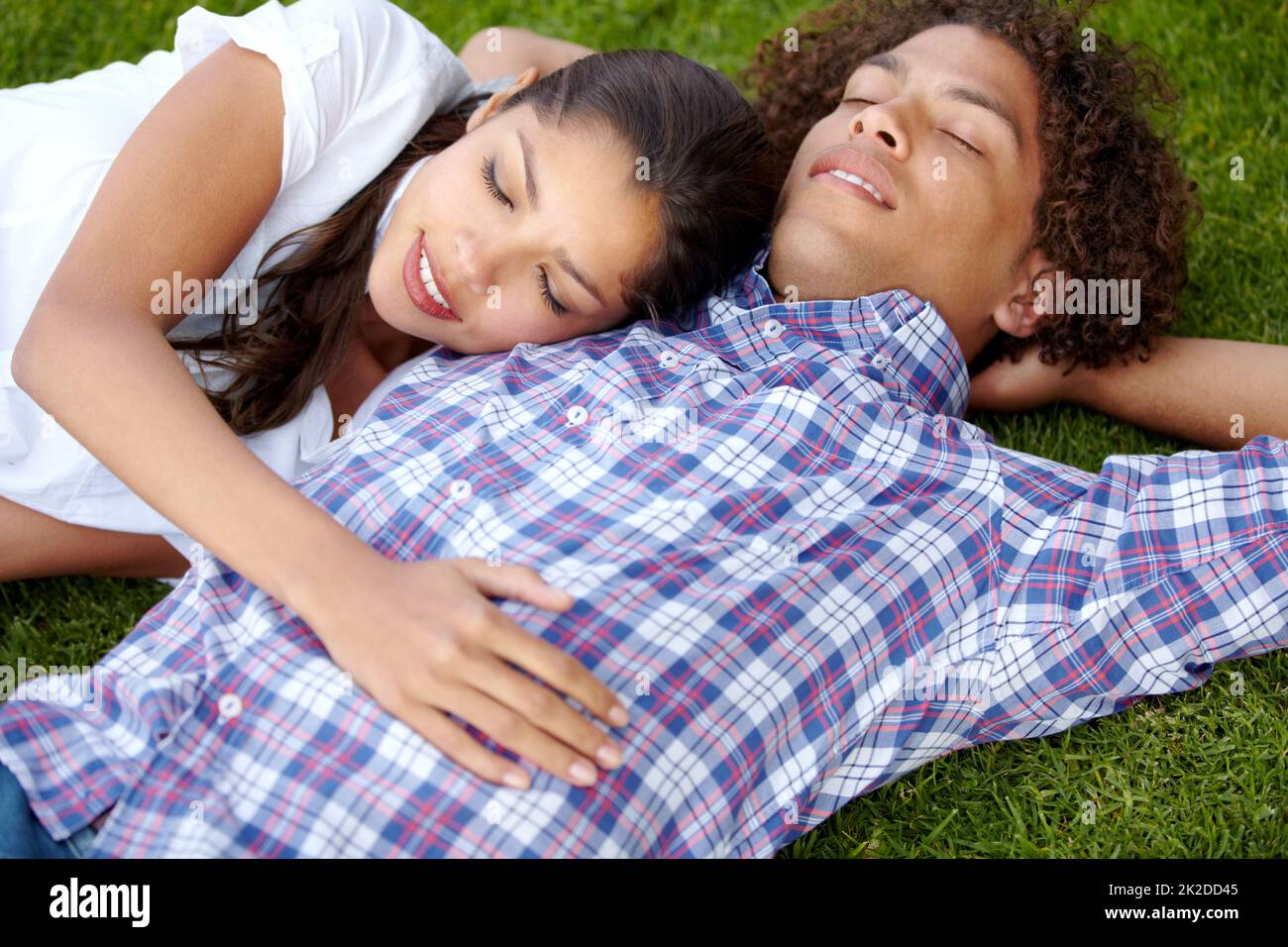 Lazy afternoon together. Shot of a happy young couple napping together on the lawn. Stock Photo