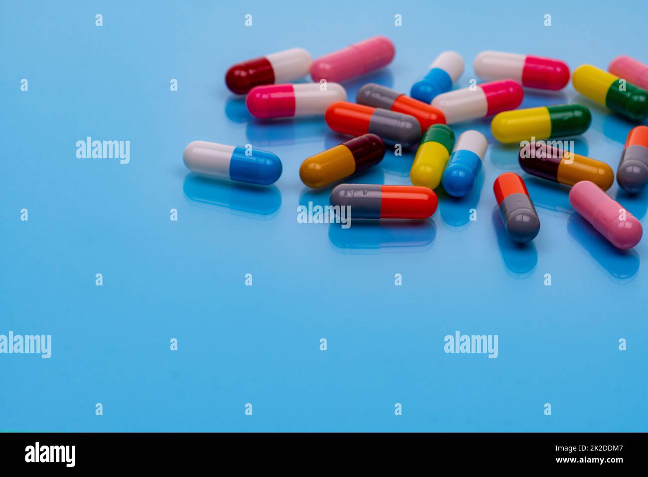 Above view colorful capsule pills on blue background. Prescription drugs. Pharmacology. Healthcare and medicine. Health budget and health policy. Many pills with space. Pharmaceutical industry. Stock Photo