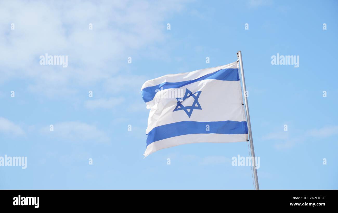 Israeli flag weaving in the wind against bright skies Stock Photo