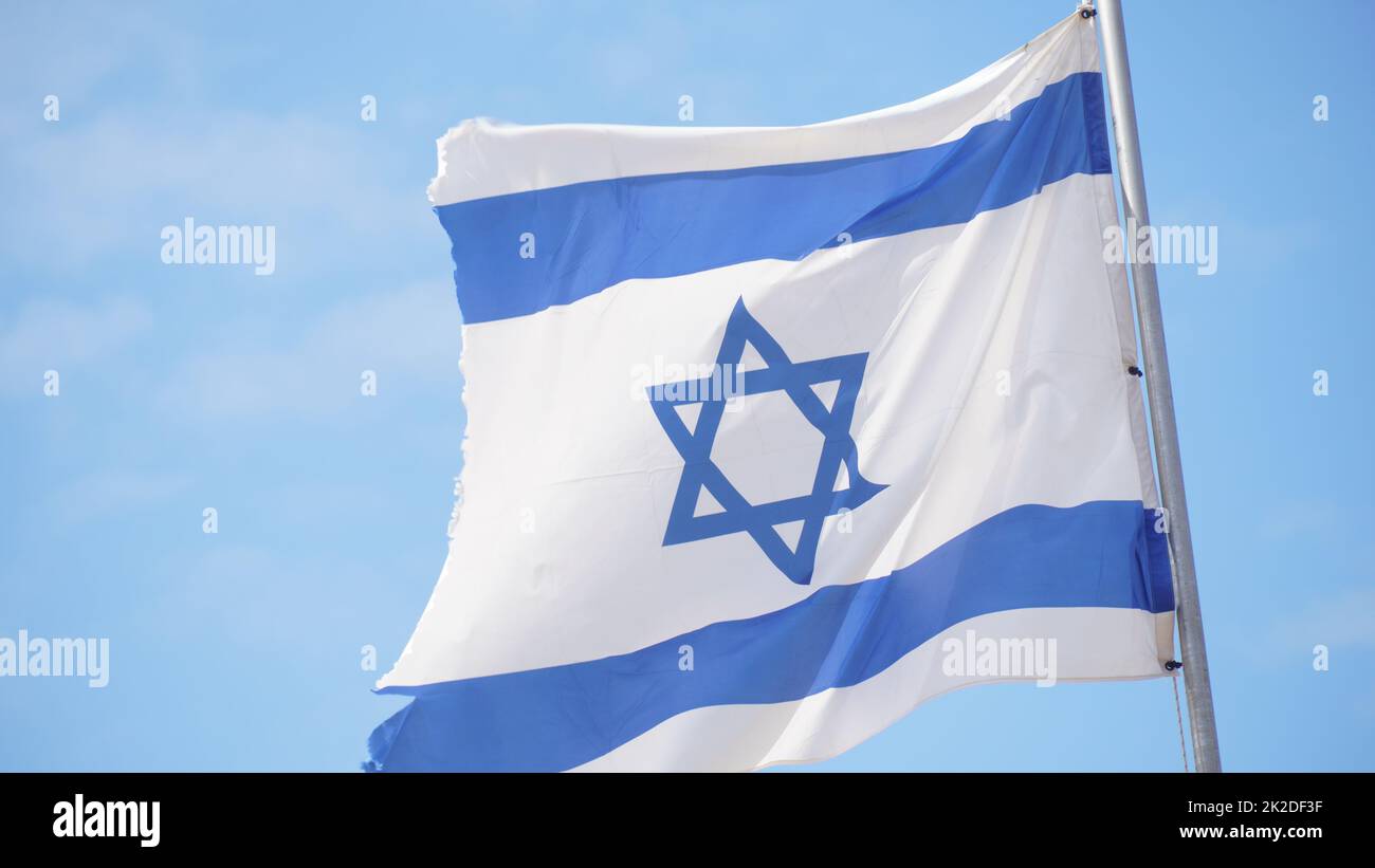 Israeli flag weaving in the wind against bright skies Stock Photo