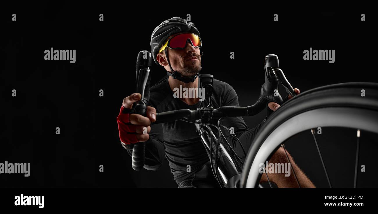 male cyclist riding road bicycle on black background Stock Photo