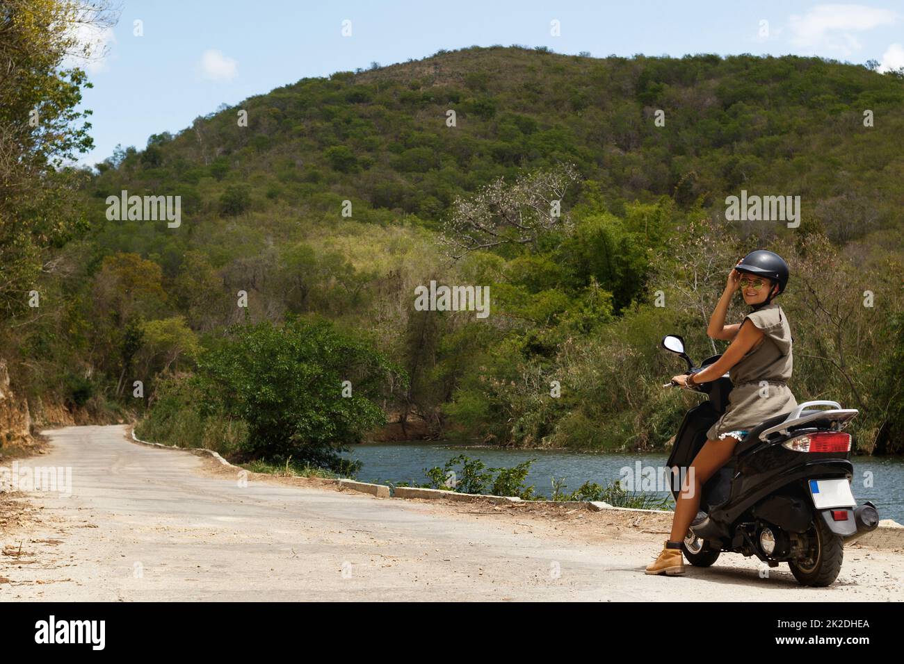 Woman driving scooter on old rural road in the mountains Stock Photo
