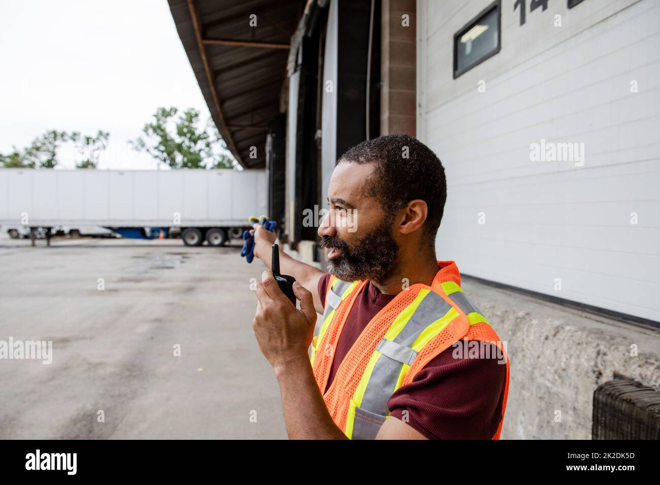 Warehouse worker using radio transceiver near loading docks Stock Photo