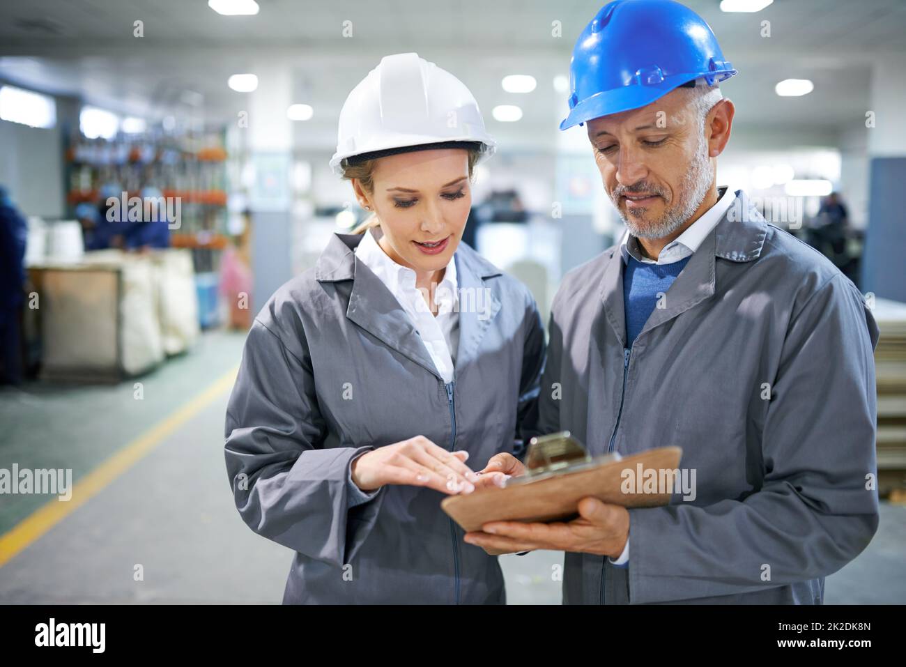 Give the order a once over. two managers standing inside a printing and packaging plant. Stock Photo
