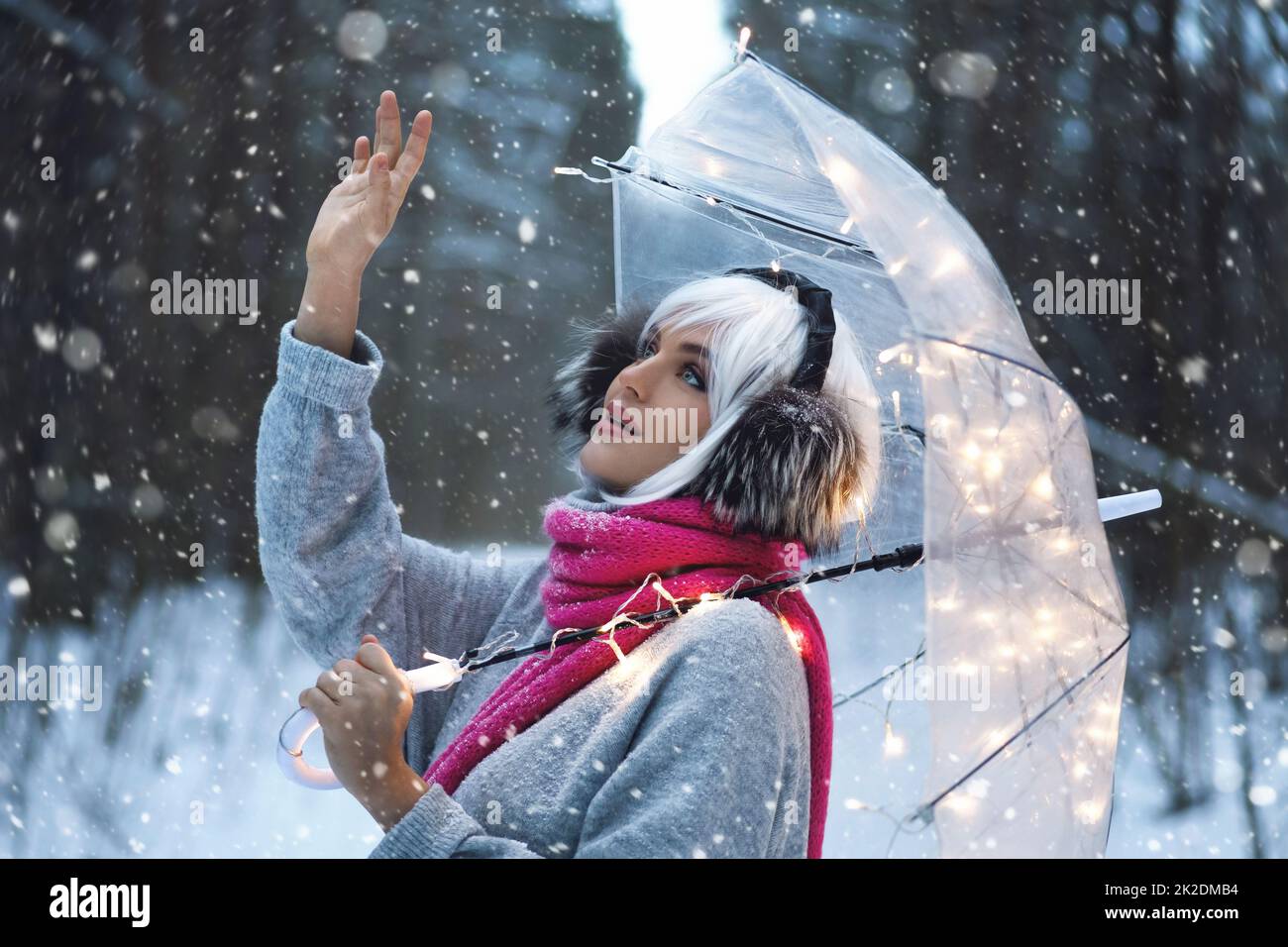 Young woman walking under transparent umbrella at snowy winter day Stock Photo