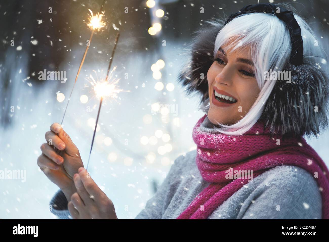 Young happy woman with sparklers in the winter snowy forest Stock Photo