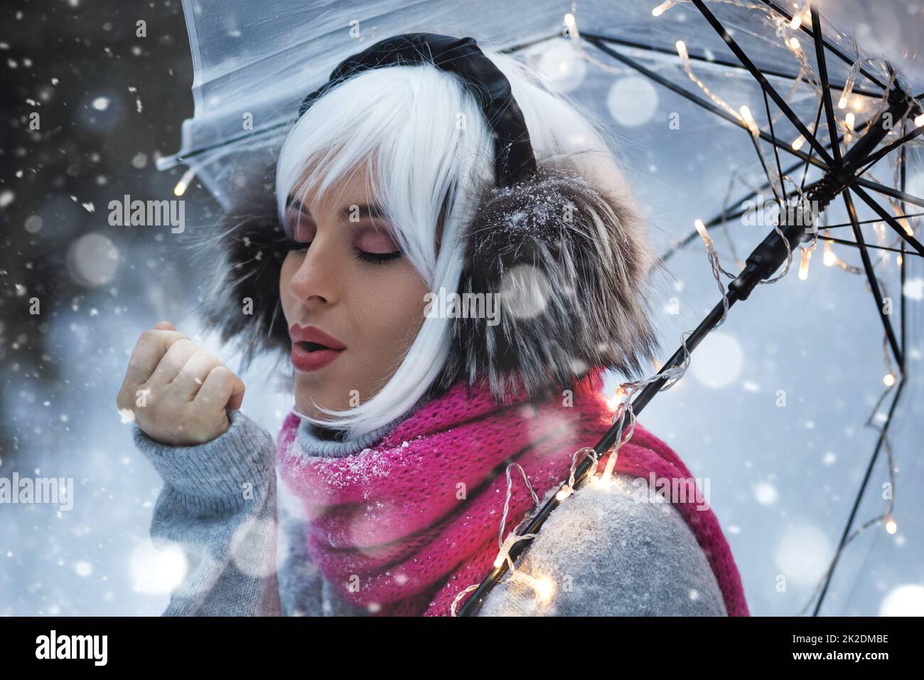 Young woman walking under transparent umbrella at snowy winter day Stock Photo