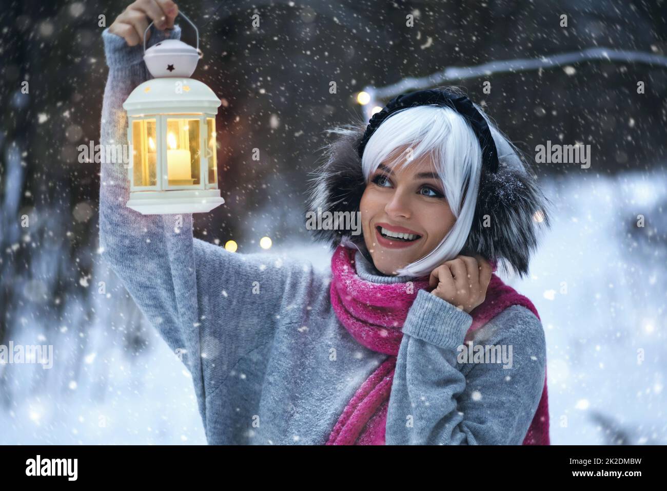 Young woman with candlelight lantern in her hand walking in the snowy winter forest Stock Photo