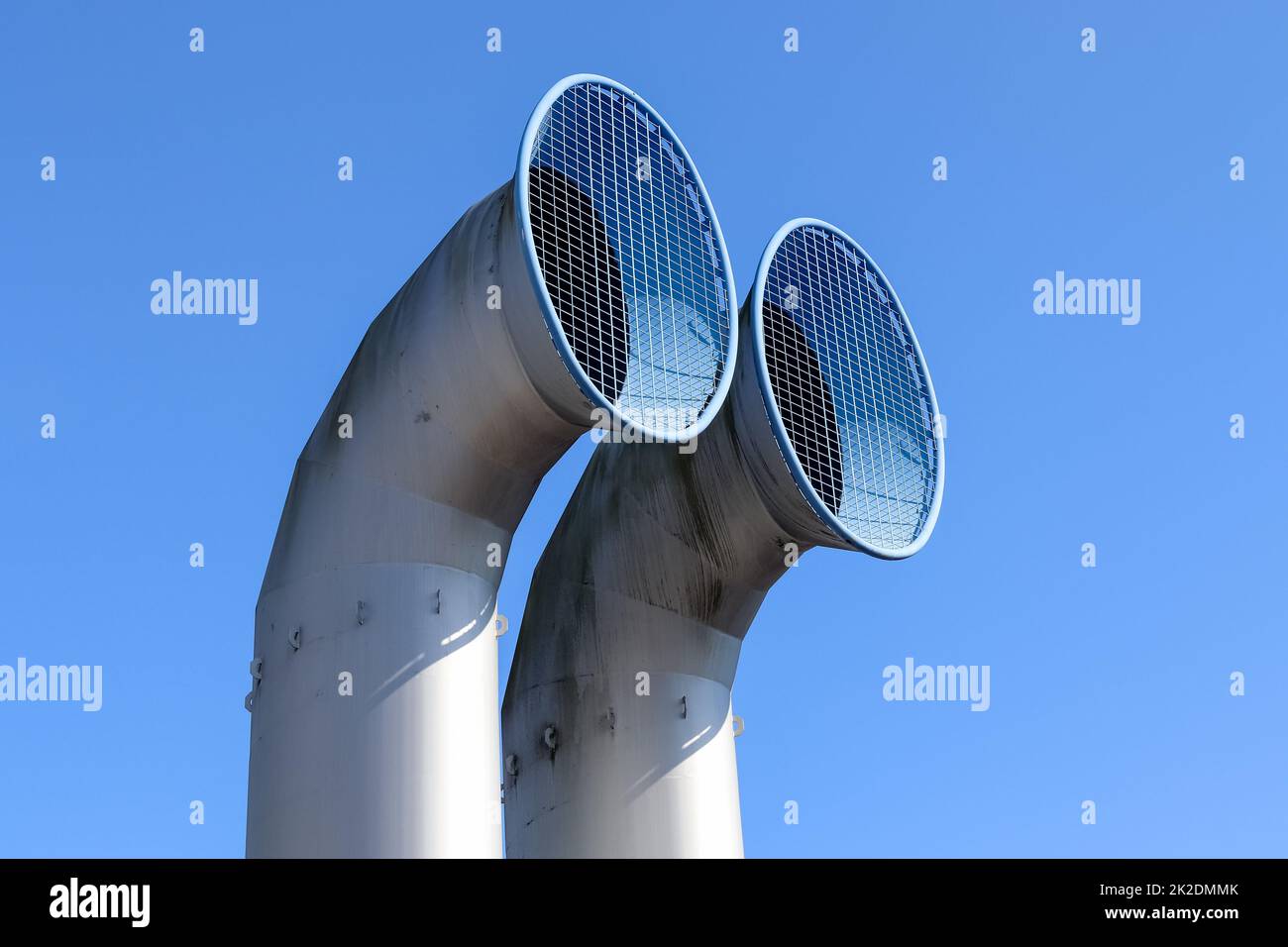 Two large chimney pipes with grids in front of them taken from below. Stock Photo