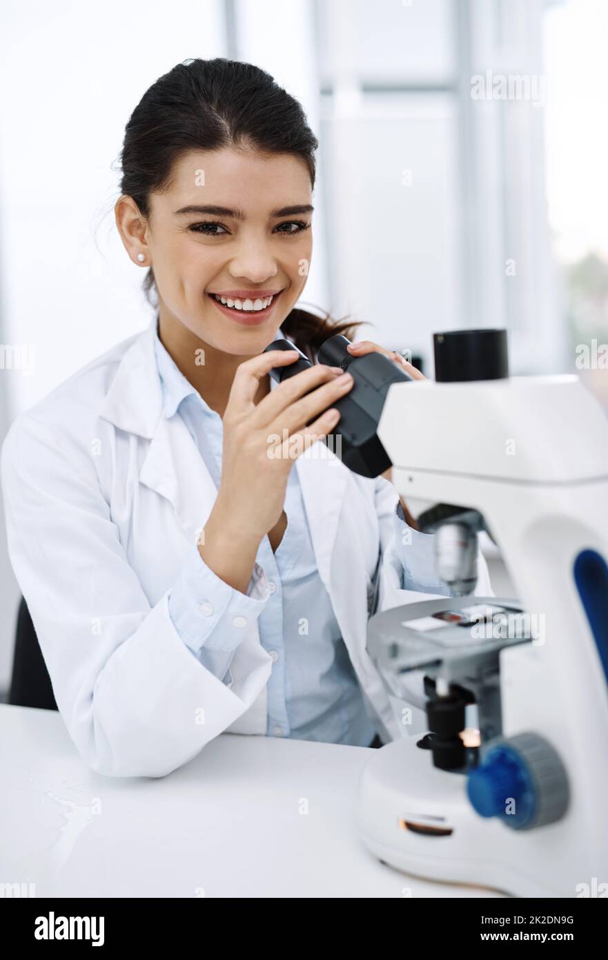 Ive always been curious about the world. Shot of a young scientist using a microscope in a lab. Stock Photo