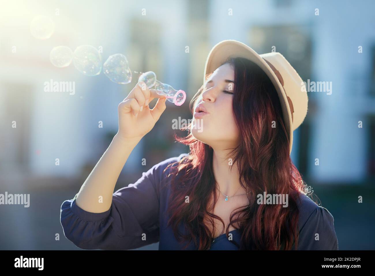 Just blow with the flow. Shot of an attractive young woman blowing bubbles outside. Stock Photo