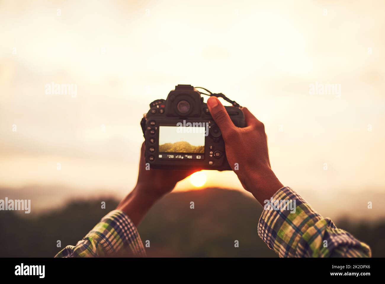 Viewing natures beauty through a lens. Closeup shot of an unidentifiable man taking a photo on a camera outside. Stock Photo