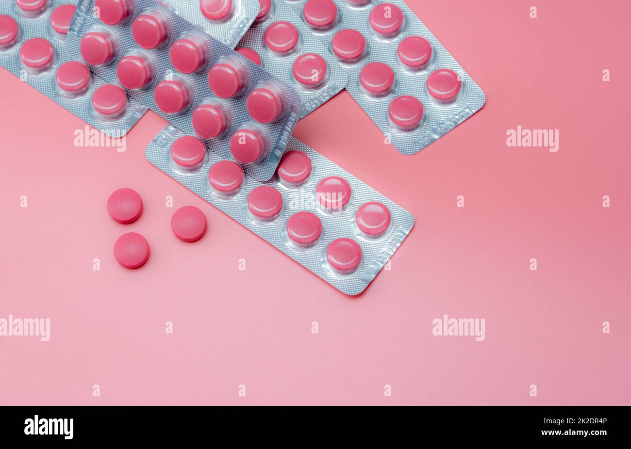 Top view pink tablet pills and blister pack of pills on pink background. Prescription drug. Vitamins, minerals, and supplements. Pharmaceutical industry. Health care and medicine. Pharmacy product. Stock Photo