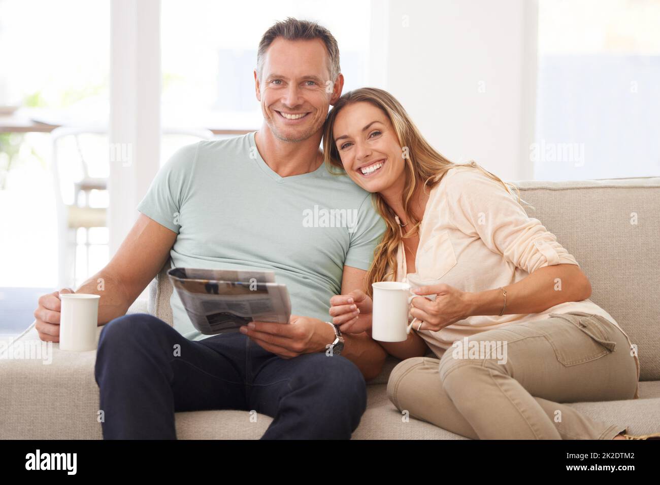 Sharing the morning paper. Portrait of a happily married couple reading the newspaper on their sofa. Stock Photo