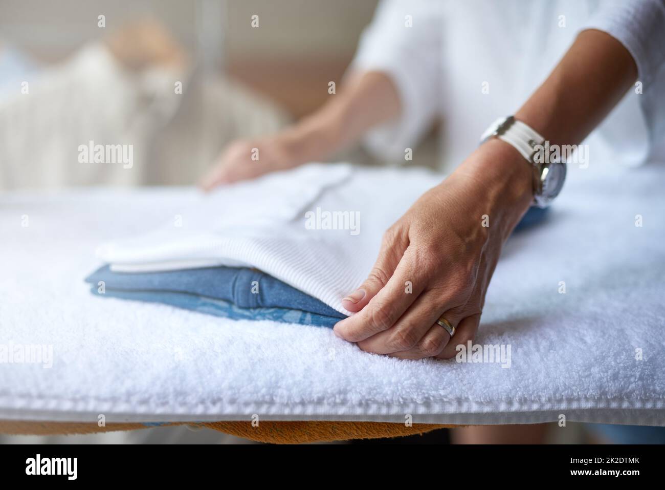 Keeping laundry neat. Closeup of a woman folding some clothes that have been ironed. Stock Photo