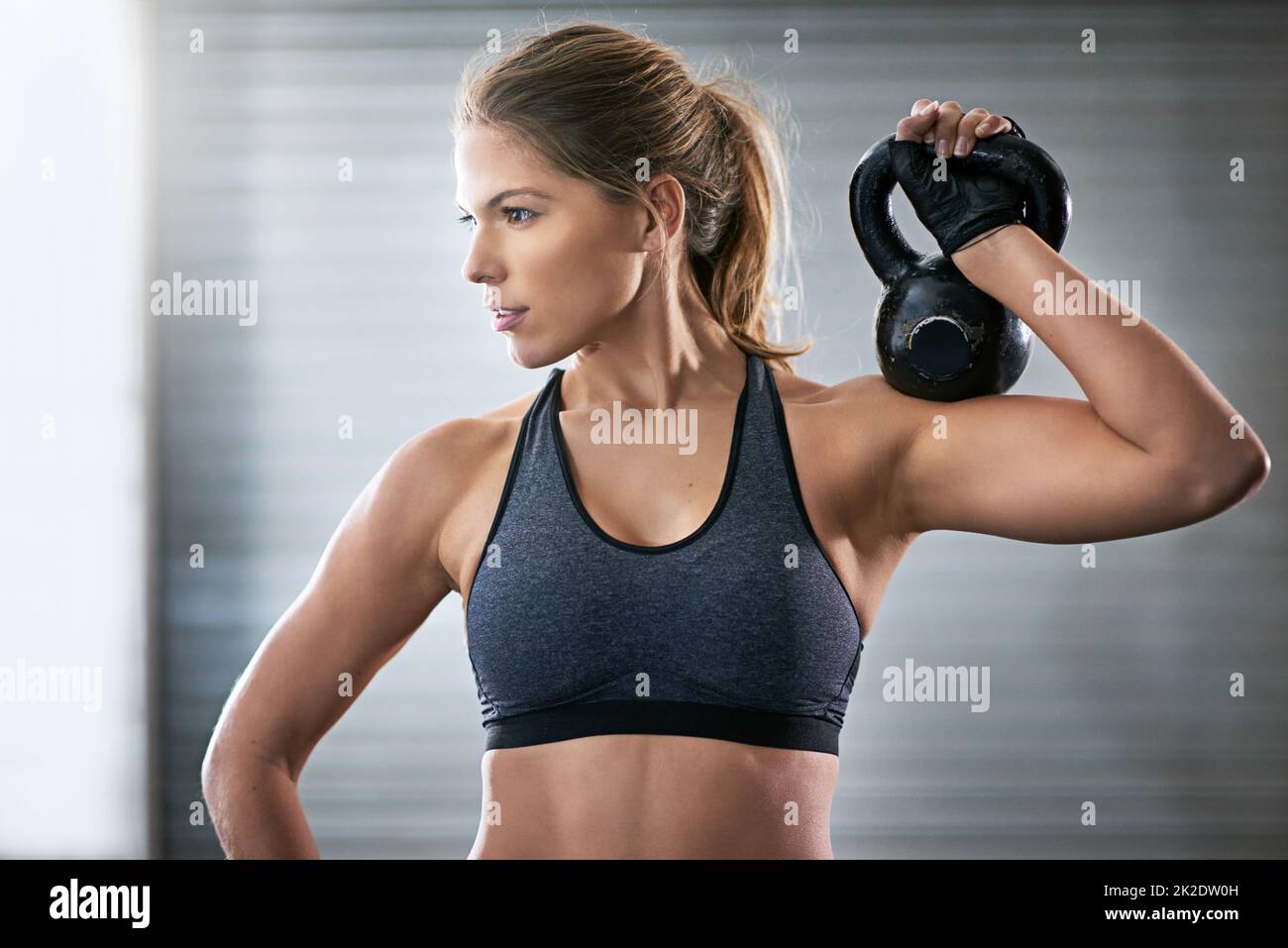Building her upper body strength. Shot of a young woman working out with a kettle bell at the gym. Stock Photo