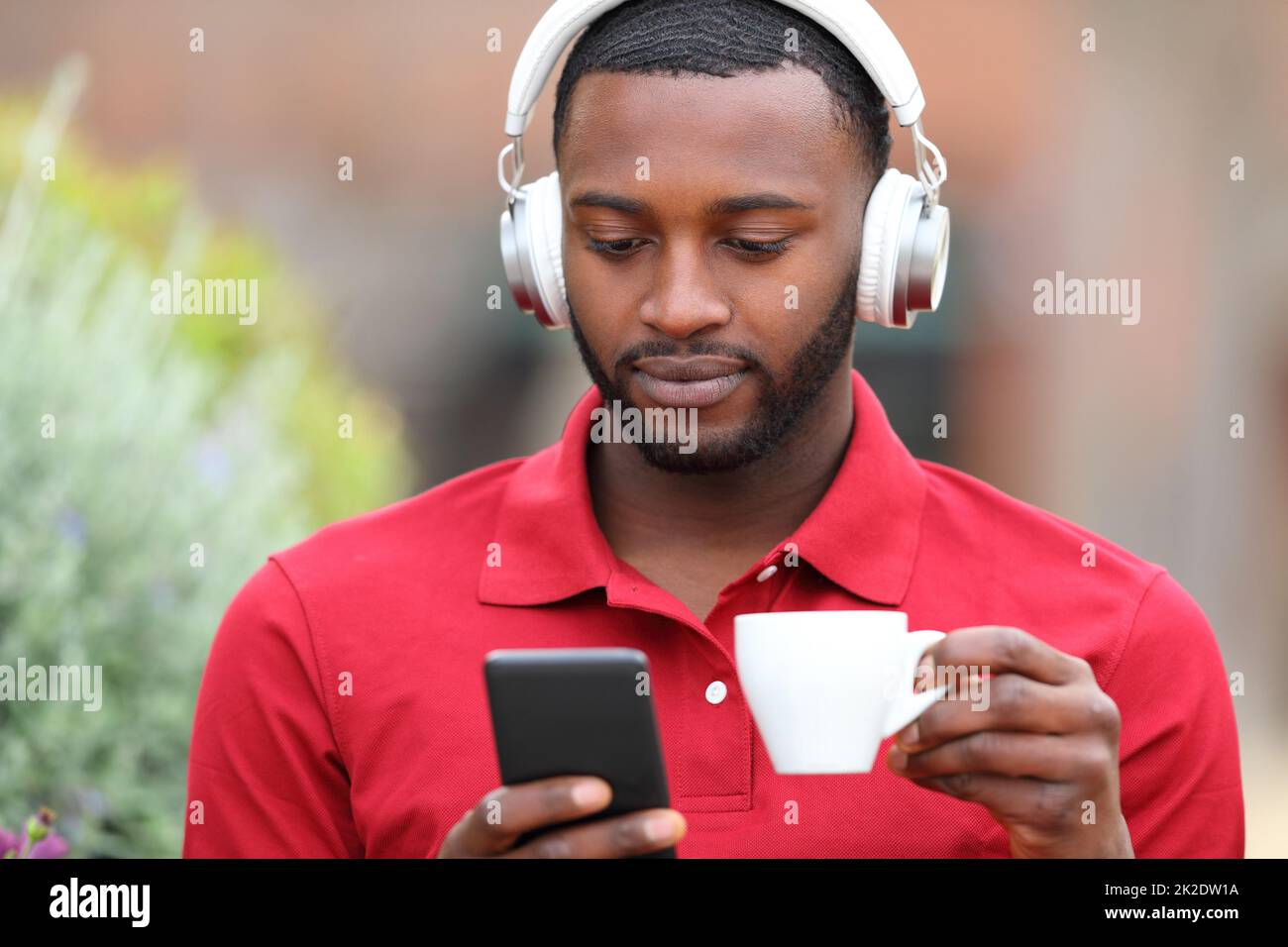 Man with black skin watcking media on phone in a bar Stock Photo