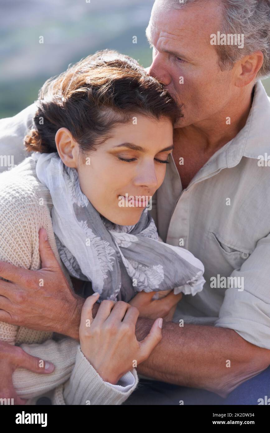 She appreciates his support and love. A loving couple hugging each other affectionately outdoors. Stock Photo