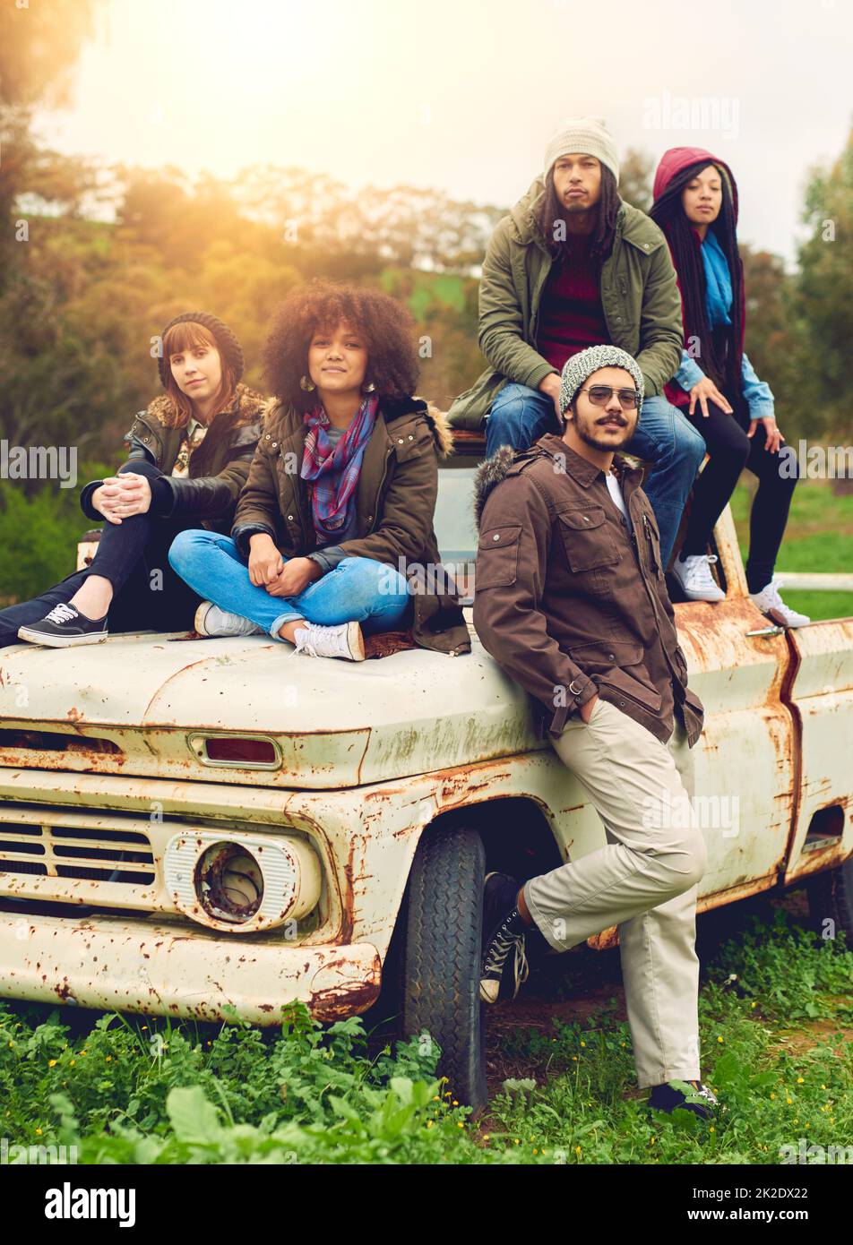 The best thing about memories is making them. Portrait of a group of friends posed around an old truck in a field. Stock Photo