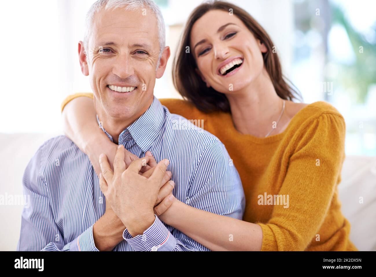 Laughing through life together. Shot of a mature man being hugged by his younger wife. Stock Photo