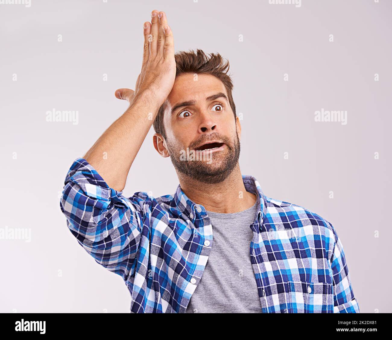 Duh. Studio shot of a young man looking forgetful against a gray background. Stock Photo