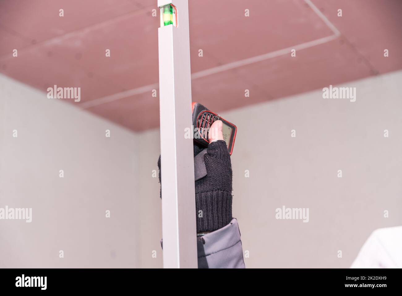 Technician measuring the distance with an infrared measuring device and a spirit level Stock Photo