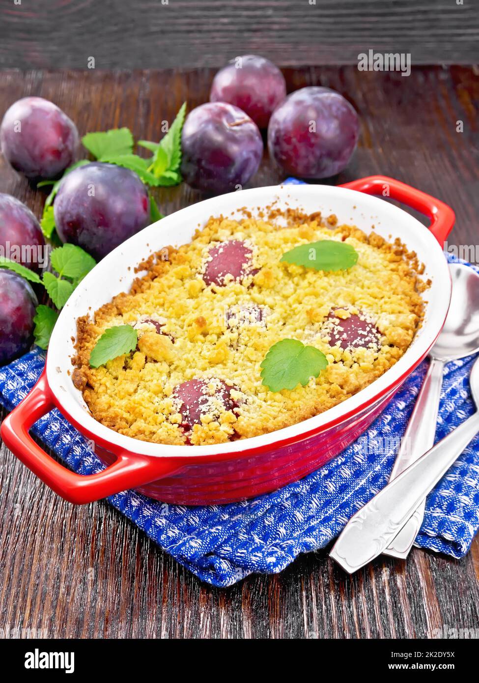 Crumble with plum in brazier on wooden board Stock Photo