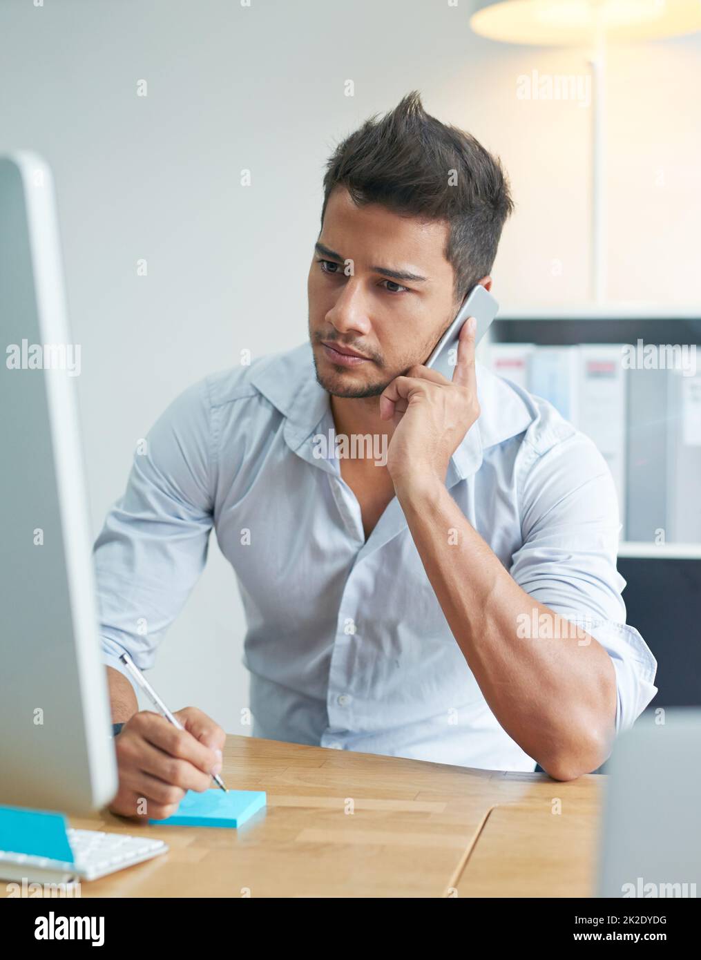 This news could have a negative effect on business. Shot of a worried businessman talking on his phone while looking at his computer. Stock Photo