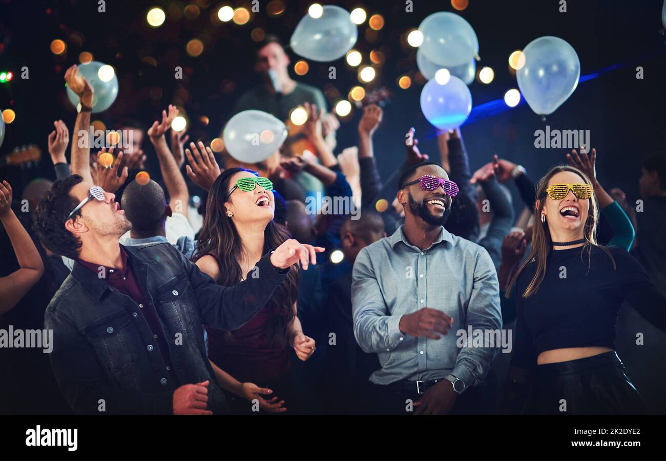 Its going down. Cropped shot of a diverse group of young friends having fun with balloons at a party at night. Stock Photo