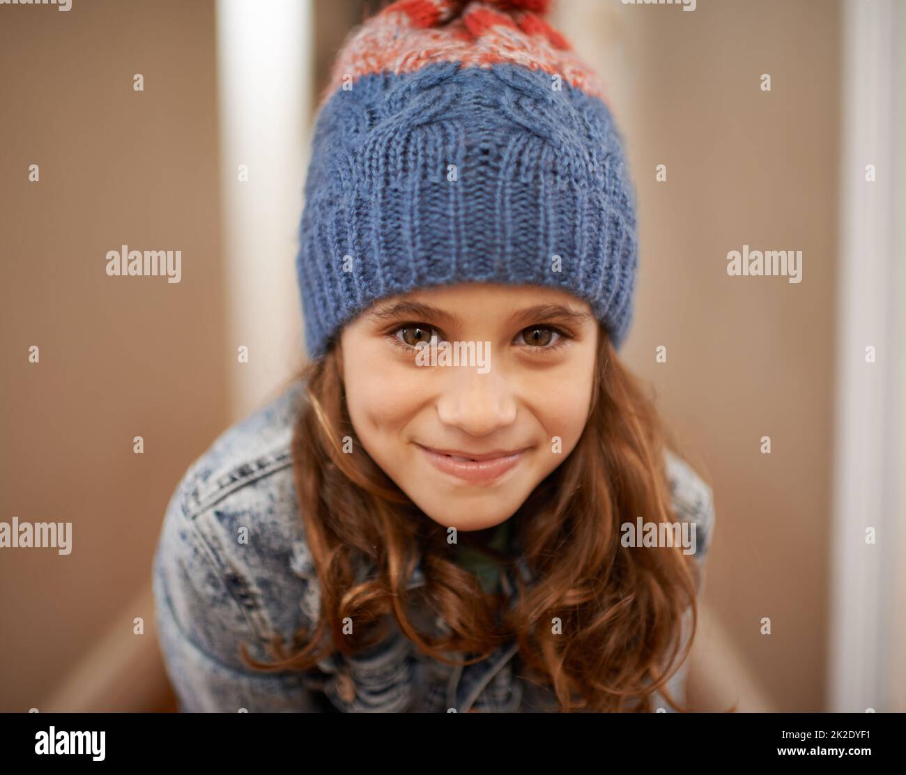 Time for some vacation fun. Shot of a young girl posing in her woolen hat indoors. Stock Photo