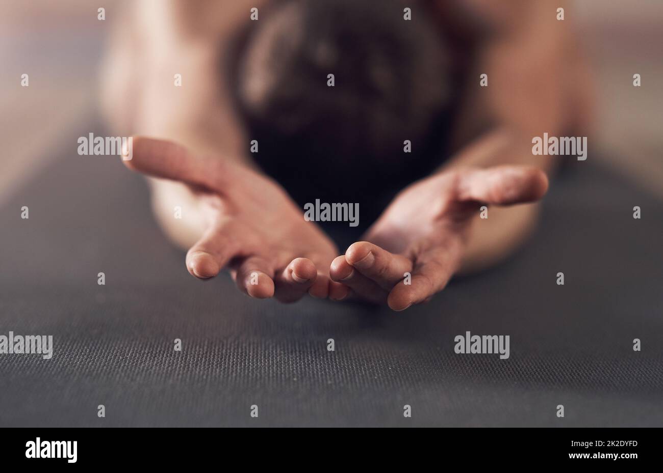 I surrender myself to the zen. Shot of an unrecognizable man stretching and practicing yoga indoors. Stock Photo