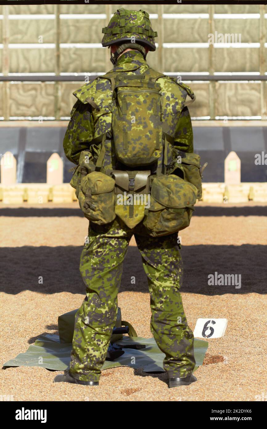 Full metal jacket. Rearview shot of a young soldier in his uniform with his gear in front of him. Stock Photo