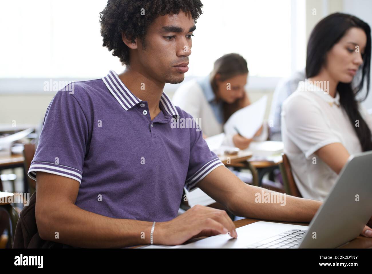 Immersed in his project. Shot of a group of university students working on laptops in class. Stock Photo
