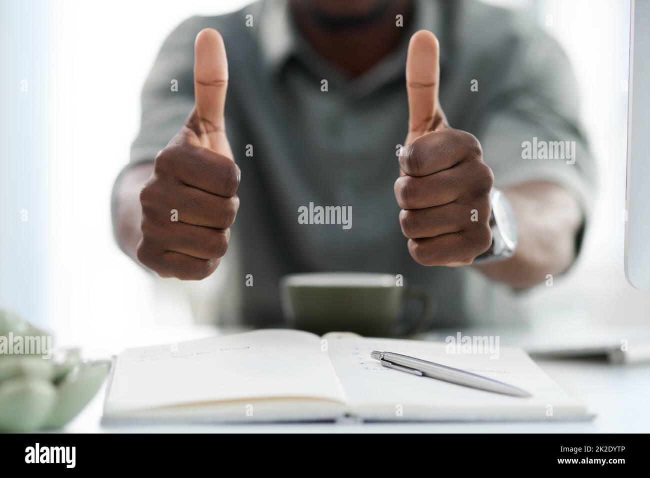 Everything will work out. Cropped shot of a young man showing thumbs up at work. Stock Photo
