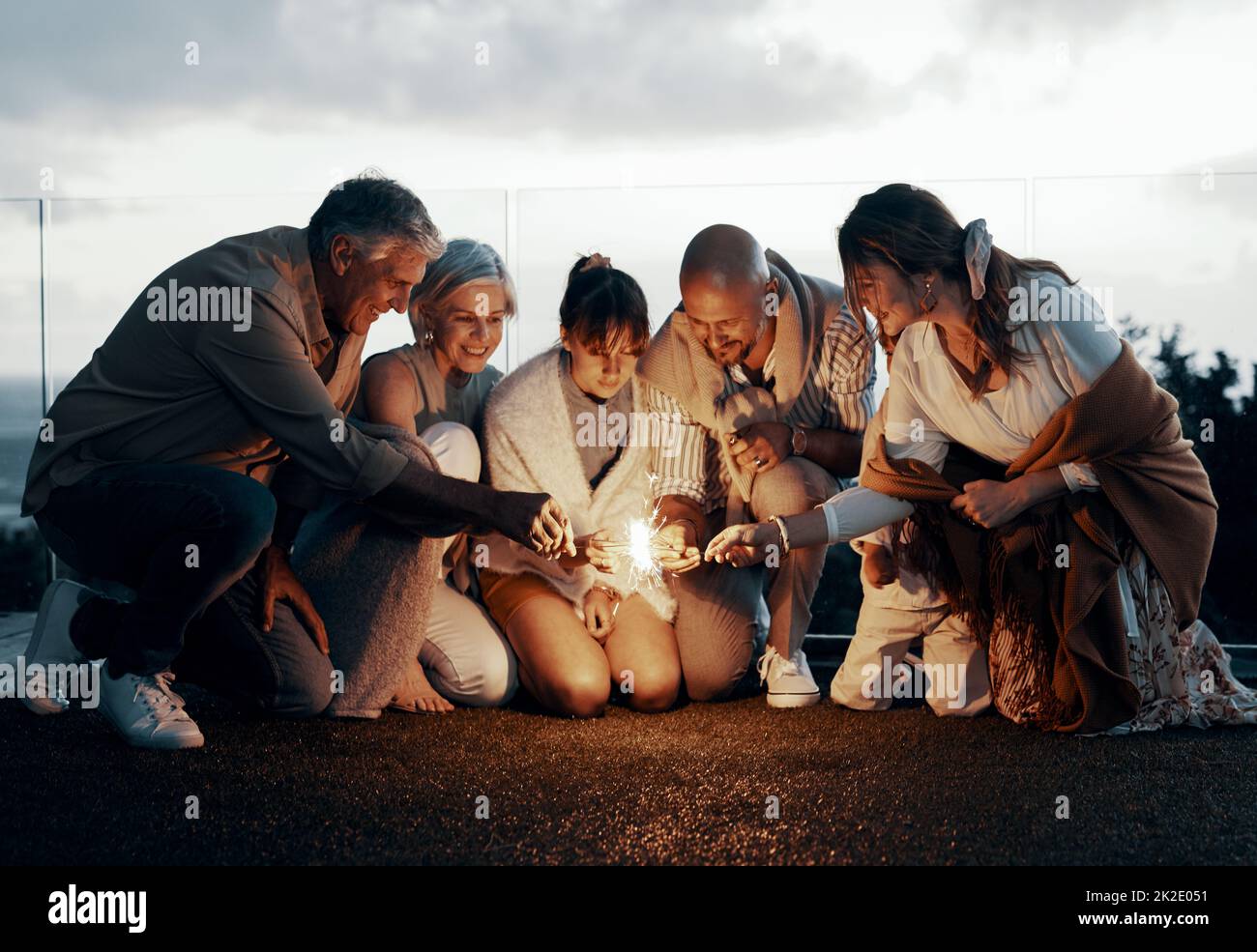 Its time for some lights. Full length shot of an affectionate family lighting up sparklers while celebrating a new year outdoors. Stock Photo