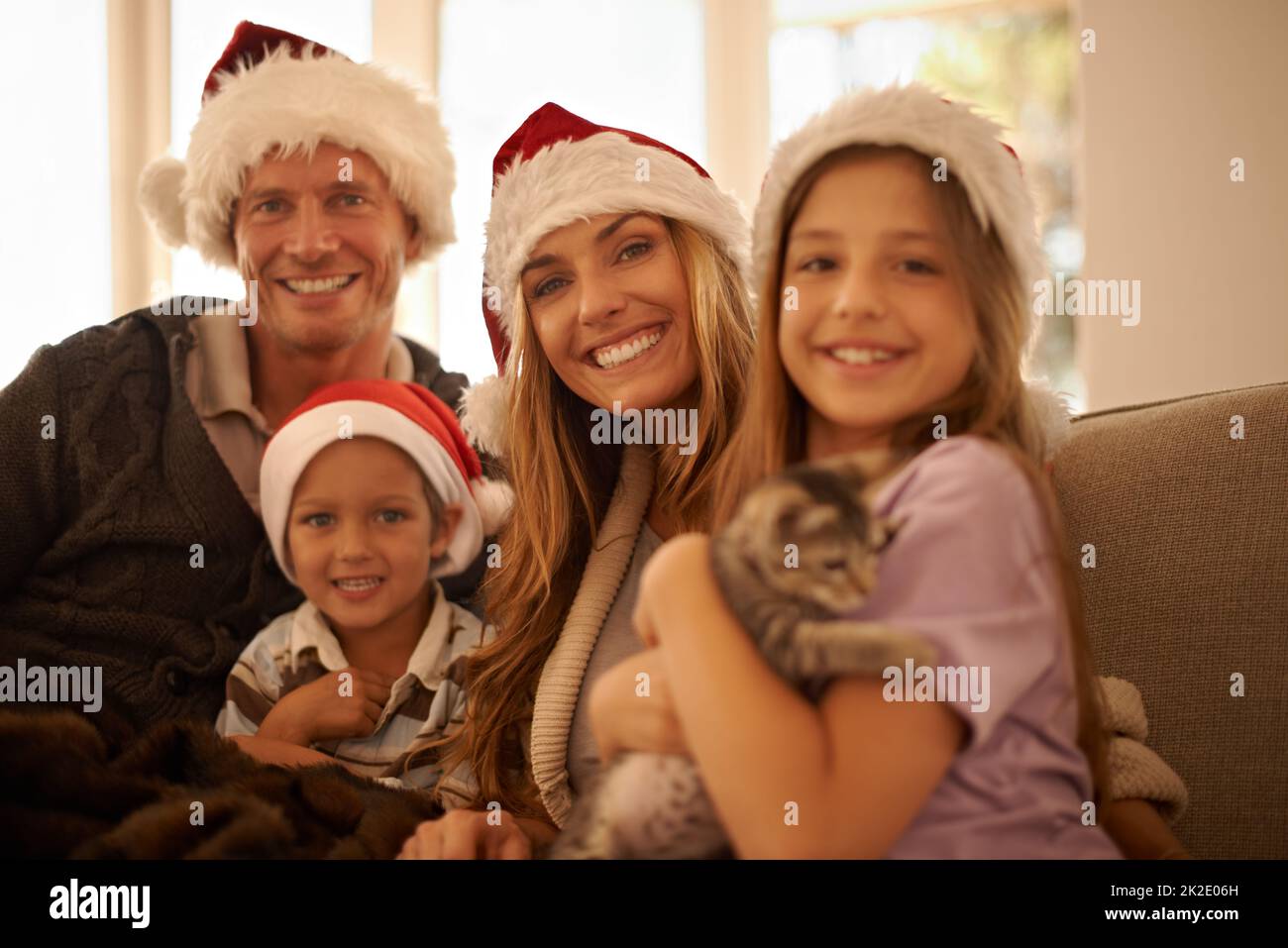 Look what Santa brought us. Portrait of a happy young family on Christmas day holding a new kitten. Stock Photo