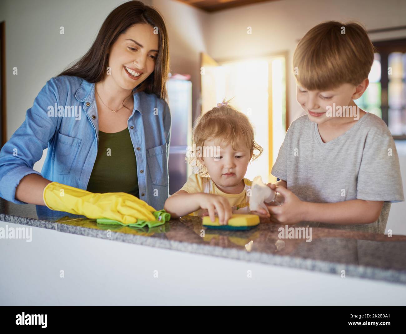 Doing chores is a great way to teach kids about responsibility. Shot of a mother and her two little children doing chores together at home. Stock Photo