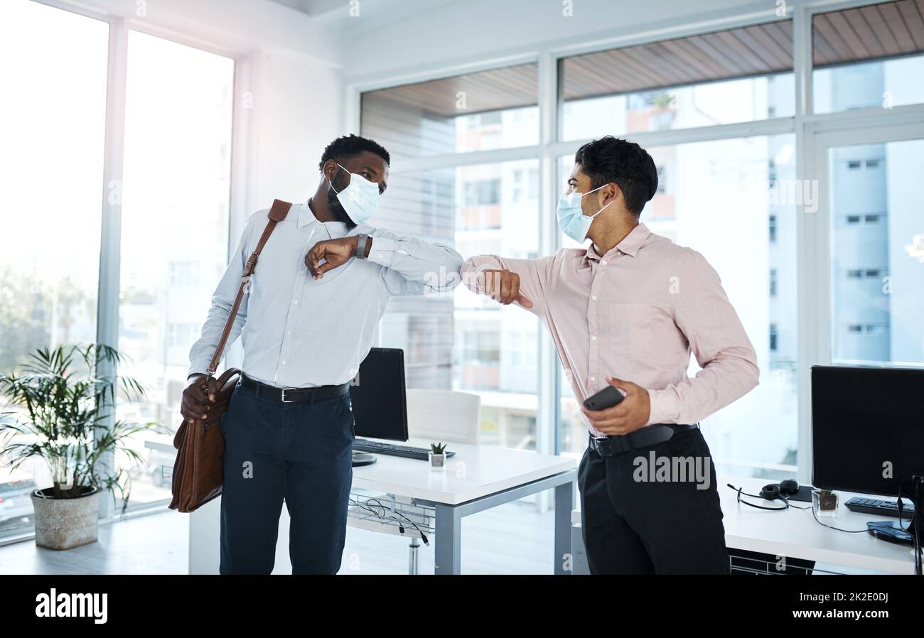 A new greeting adopted during the pandemic. Shot of two businessmen bumping elbows in an office. Stock Photo