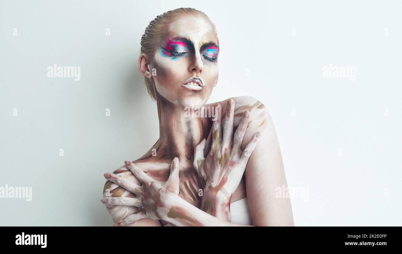 Embrace the strange. Studio shot of a young woman posing with paint on her face. Stock Photo