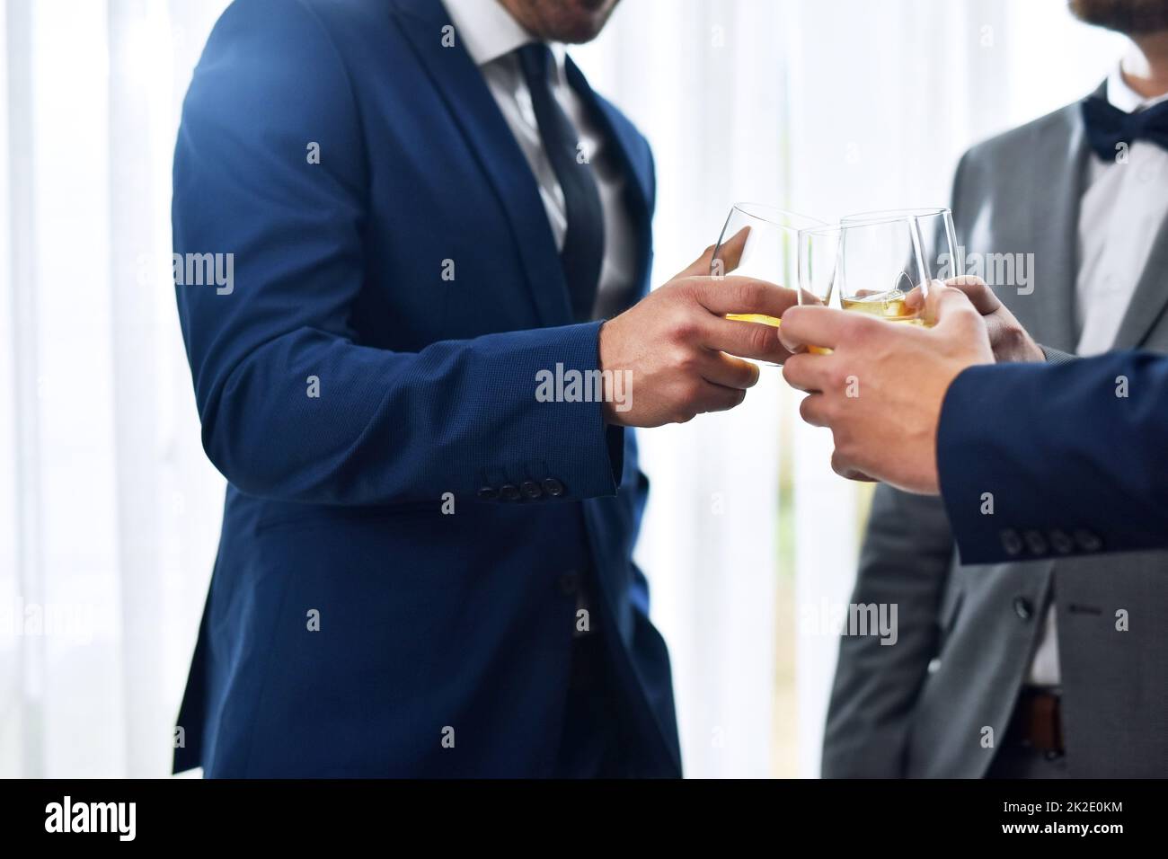 We wish you a lifetime of love and happiness buddy. Shot of two unrecognizable groomsmen sharing a toast with the bridegroom on his wedding day. Stock Photo