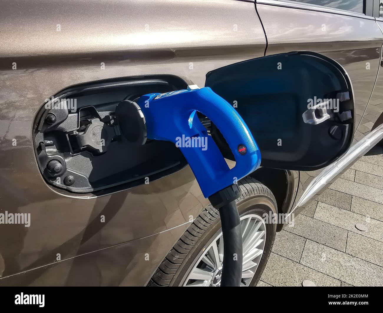 Electric car is refueled. Picture shows an electro connector and car in detail with the tank cap open Stock Photo