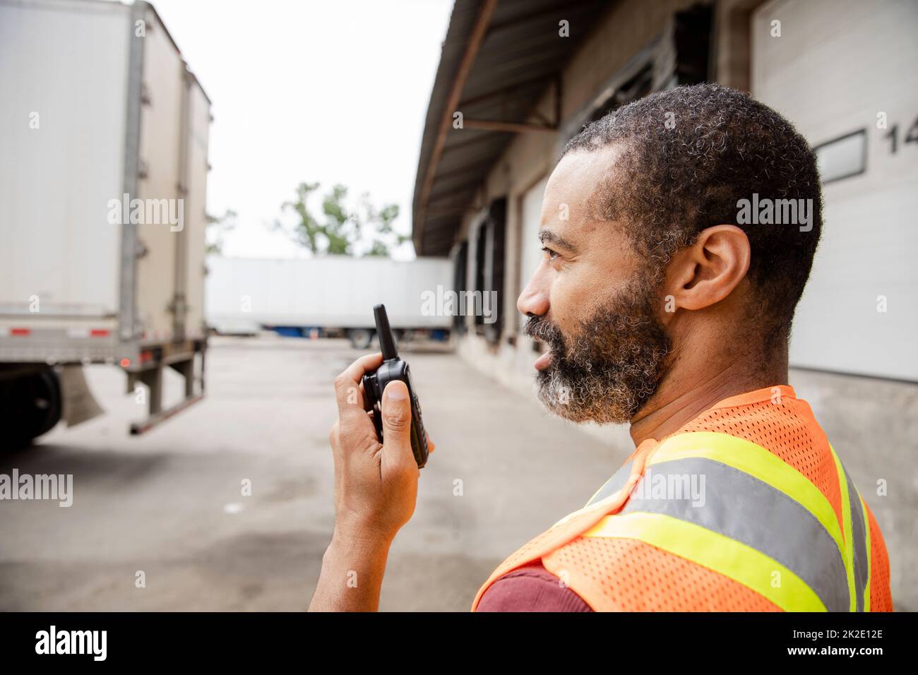 Warehouse worker using radio transceiver near loading docks Stock Photo