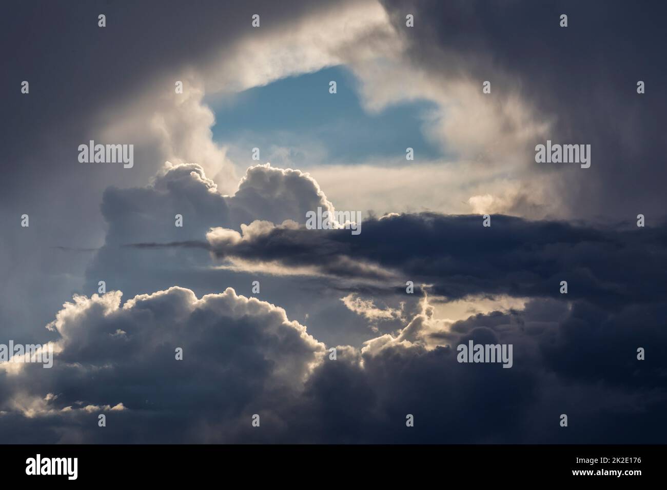 An opening in storm clouds showing blue sky beyond. Stock Photo