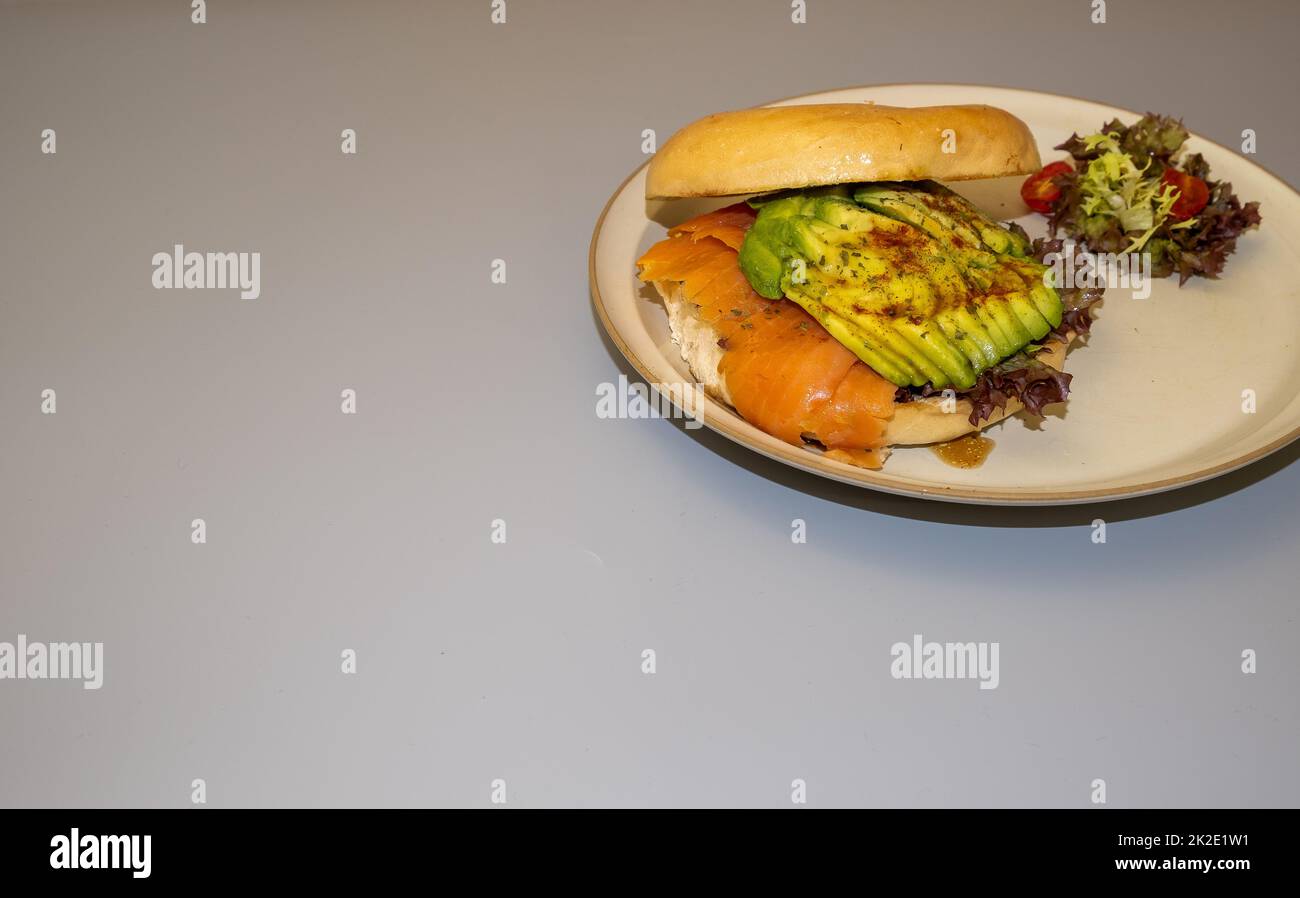 Avocado and smoked salmon bagel on a dise and gray color background Stock Photo