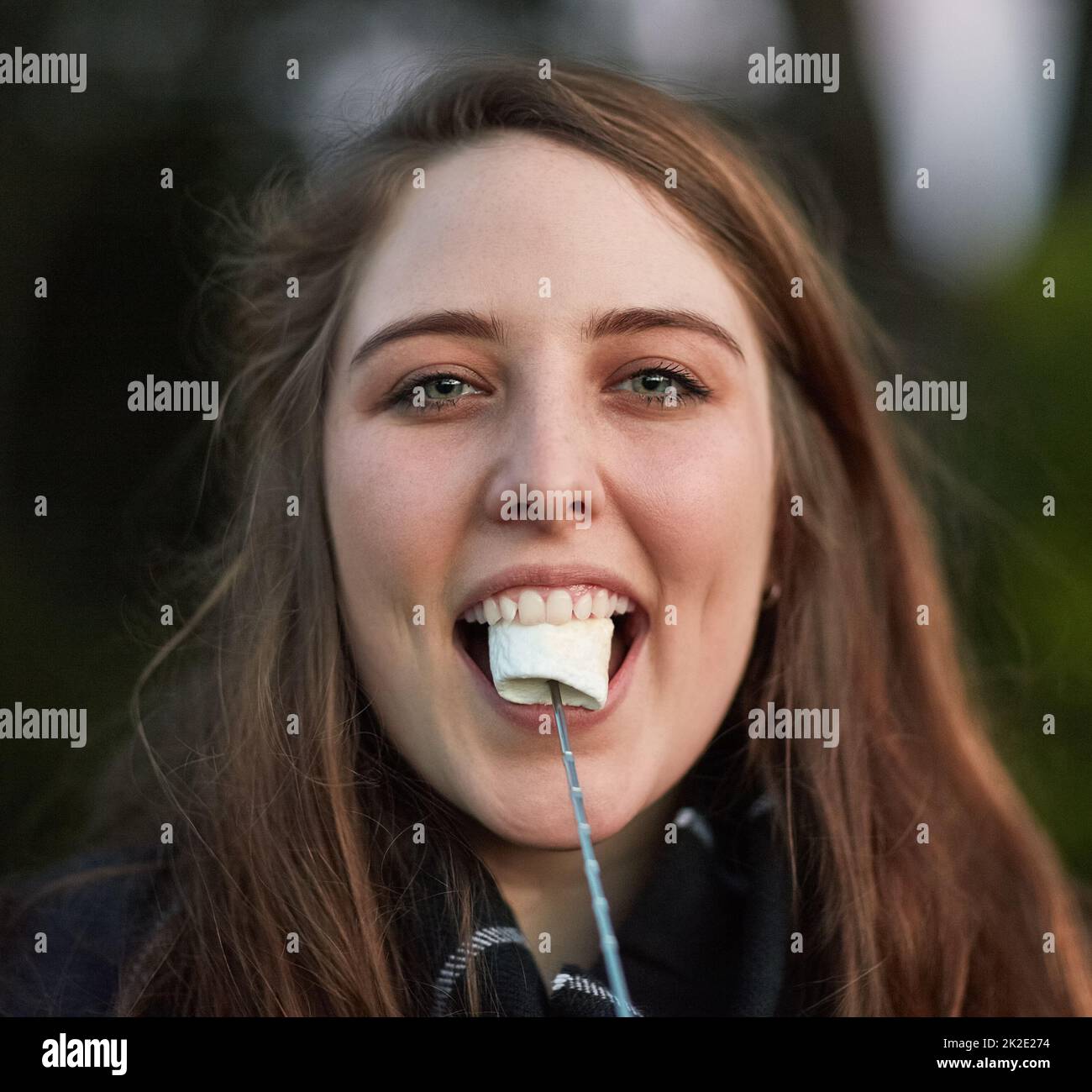 Camp life is sweet. Portrait of a pretty young woman eating a roasted