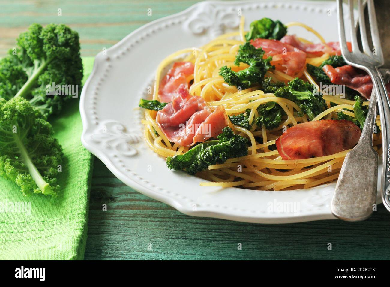 Delicious spicy linguine pasta with fried cabbage kale, bacon, garlic and parmesan on a white plate . Top view Stock Photo