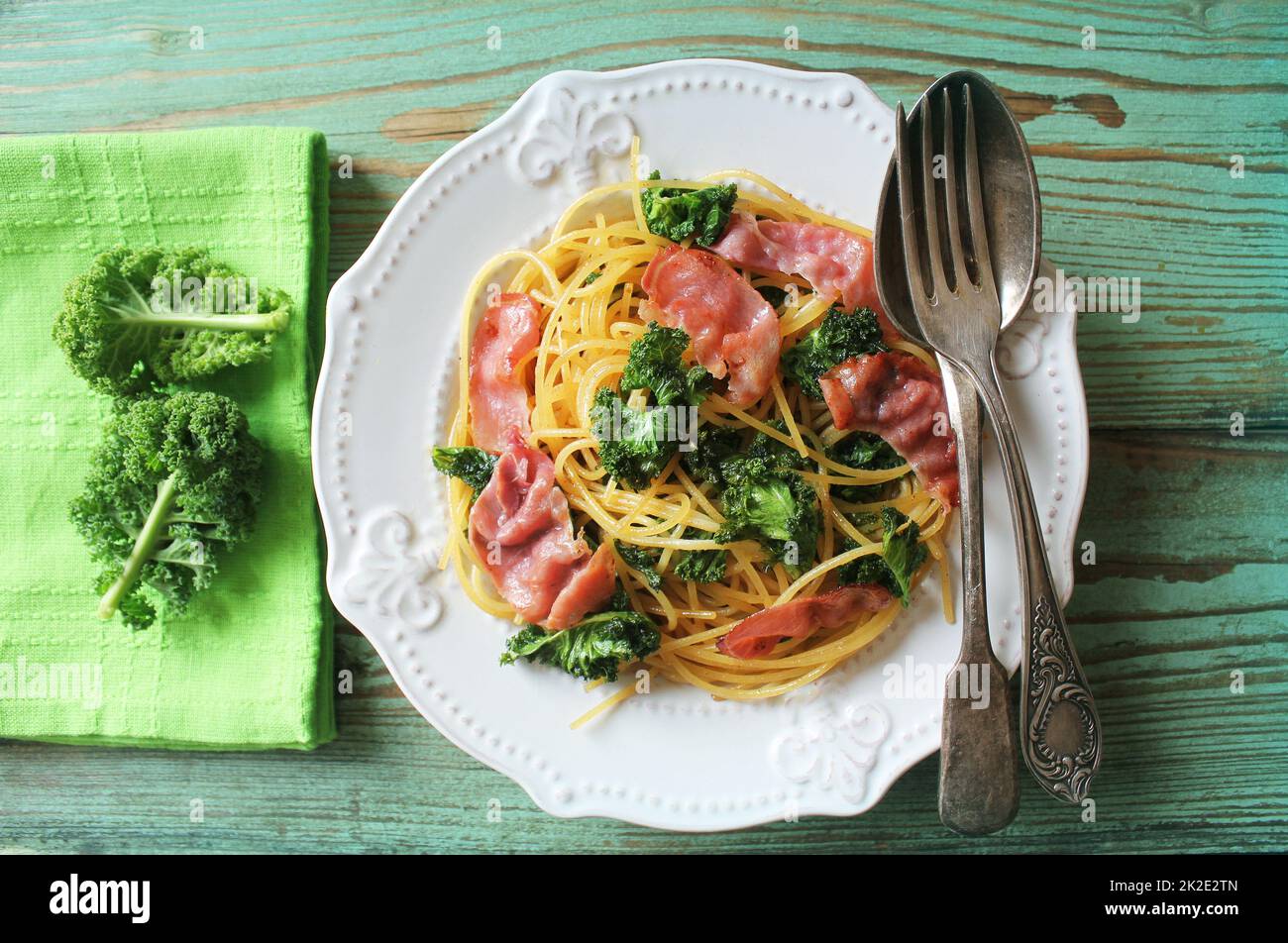 Delicious spicy linguine pasta with fried cabbage kale, bacon, garlic and parmesan on a white plate . Top view Stock Photo