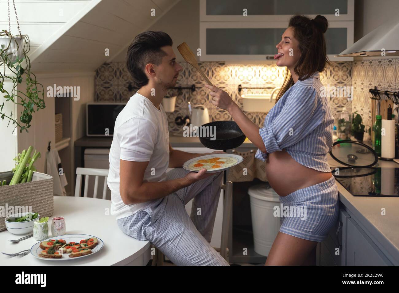 Husband and his pregnant wife on the kitchen during breakfast time